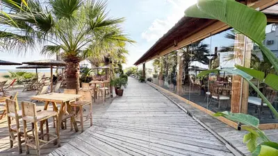a wooden walkway with tables and chairs on a beach at Seaside Larnaca Makenzie- 50m to Beach in Larnaka