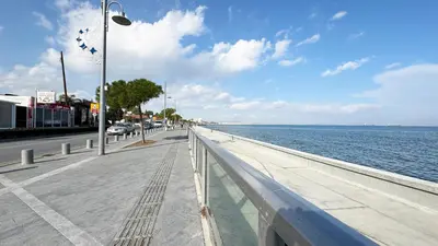 a sidewalk next to the ocean with a street light at Seaside Larnaca Makenzie- 50m to Beach in Larnaka