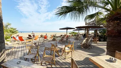 a deck with chairs and umbrellas on the beach at Seaside Larnaca Makenzie- 50m to Beach in Larnaka