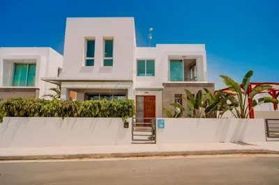 a white house with a white fence and trees at Alasia 16 - Modern smart villa in tranquil serenity in Paralimni