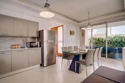 a kitchen and dining room with a table and a refrigerator at Alasia 16 - Modern smart villa in tranquil serenity in Paralimni