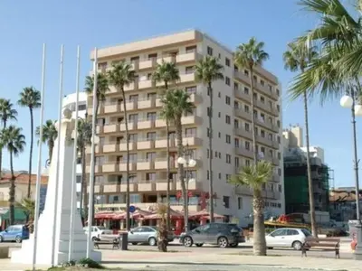 a large building with palm trees in front of it at Ithaki Phinikoudes Apartment No. 205 in Larnaka
