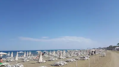 a bunch of chairs and umbrellas on a beach at Ithaki Phinikoudes Apartments No. 106 in Larnaka