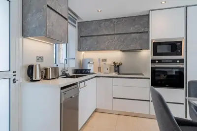 a kitchen with white cabinets and stainless steel appliances at Pervolia Seaview Escape in Pervolia
