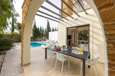 a dining room with a table and chairs and a pool at villa Ionion H32 in Ayia Napa