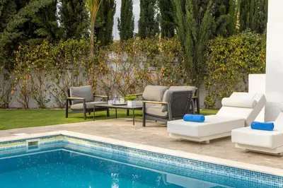 a pool with lounge chairs and a table next to a pool at villa Ionion H32 in Ayia Napa