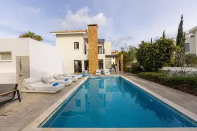 a swimming pool with lounge chairs next to a house at villa Ionion H32 in Ayia Napa
