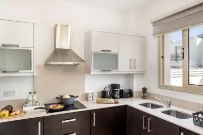 a kitchen with white cabinets and a sink at Villa Palms 32 in Protaras