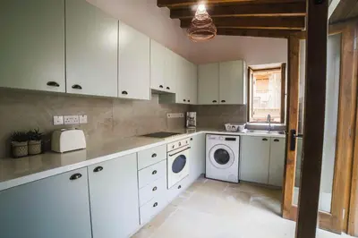 a kitchen with white cabinets and a washer and dryer at Eftychia's House in Lofou