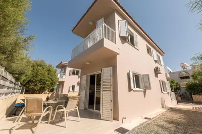 a white house with a table and chairs at Villa Marina in Ayia Napa