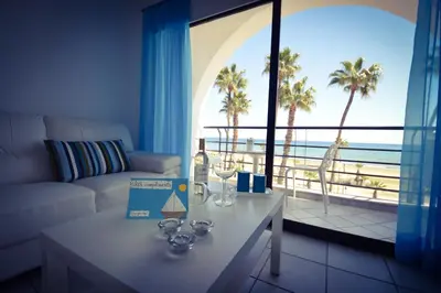 a living room with a couch and a view of the ocean at Krasas Beach Apartment Rentals in Larnaka