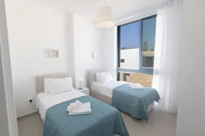 a white room with two beds and a window at Protaras Aqua Pearl Villa in Protaras