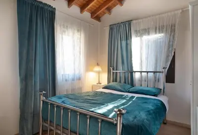 a bedroom with a bed with blue sheets and windows at Orama Mountain Villa Farmakas in Nicosia
