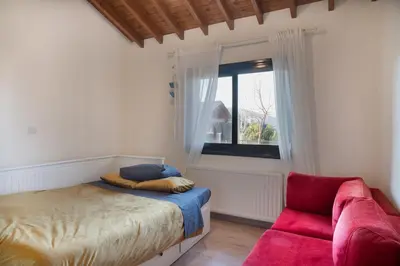 a bedroom with a bed and a window and a red couch at Orama Mountain Villa Farmakas in Nicosia