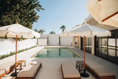 a swimming pool with two umbrellas and chairs and a pool at Hyperion Boutique Villa in Voroklini