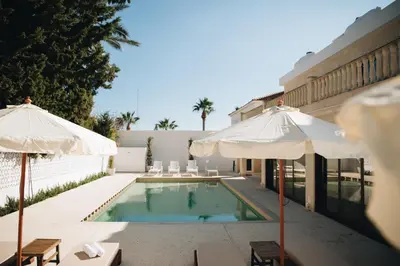 a swimming pool with two umbrellas and a building at Hyperion Boutique Villa in Voroklini