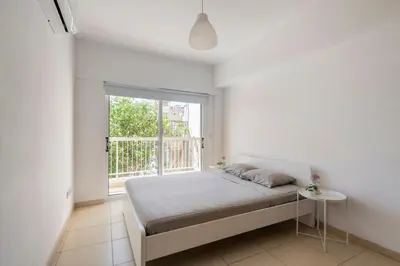 a white bedroom with a bed and a window at Center, Walking to the Beach in Larnaka