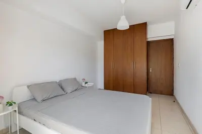 a bedroom with a white bed and a wooden cabinet at Center, Walking to the Beach in Larnaka