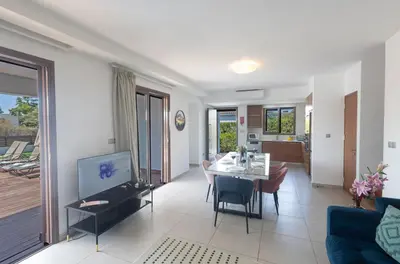 a living room with a table and chairs and a television at Sea Satin Villas - Ayia Napa Center in Ayia Napa