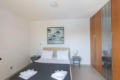 a bedroom with a bed with white sheets and two tables at Sea Satin Villas - Ayia Napa Center in Ayia Napa