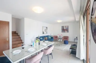 a living room with a table and pink chairs at Ayia Napa Satin Villa SVI3 in Ayia Napa
