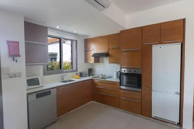 a kitchen with wooden cabinets and a white refrigerator at Ayia Napa Satin Villa SVI3 in Ayia Napa