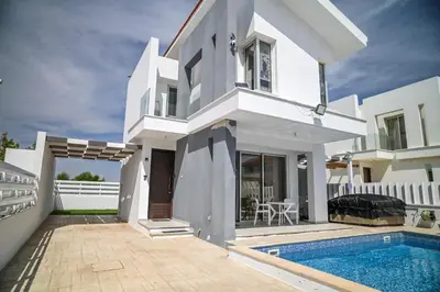 a white house with a swimming pool in front of it at Hi royal villa in Pervolia