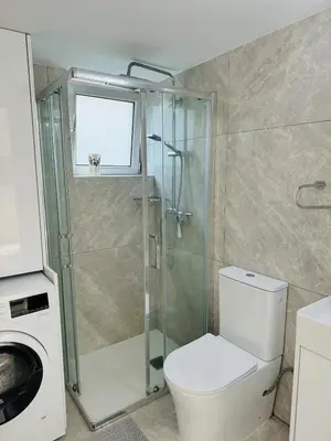 a bathroom with a toilet and a glass shower at White 1-bdr apartment Agyos Tychonas in Limassol