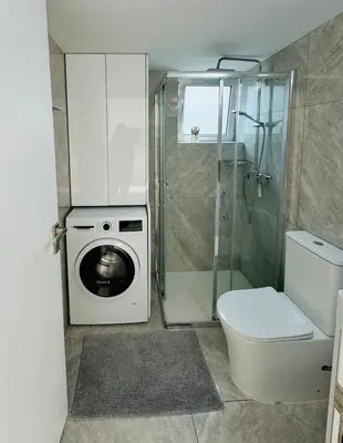 a bathroom with a washing machine and a toilet at White 1-bdr apartment Agyos Tychonas in Limassol