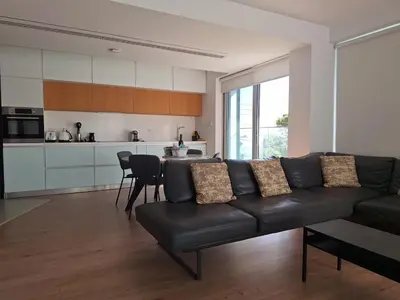 a living room with a black couch and a kitchen at Luxury Seafront 2 bedroom in Limassol