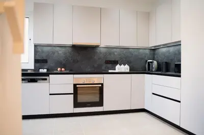 a white kitchen with black and white appliances at Delightful 1st Floor Xanthippis Apartment in Strovolos