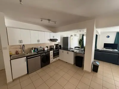a kitchen with white cabinets and a couch in a room at Kapparis Pleasure Familly Lounge in Paralimni