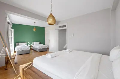 a bedroom with a white bed and a green wall at St Lazar Penthouse Apartment in Larnaka