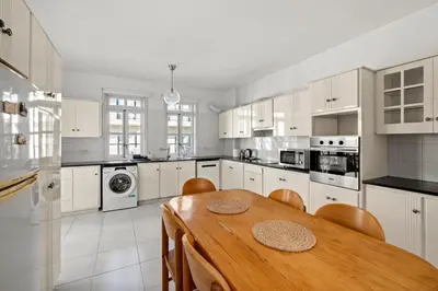 a kitchen with a wooden table and white cabinets at St Lazar Penthouse Apartment in Larnaka