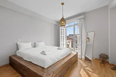 a white bedroom with a large bed and a large window at St Lazar Penthouse Apartment in Larnaka