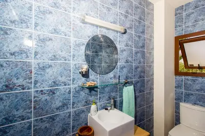 a blue tiled bathroom with a toilet and a mirror at Gold Sand Villa in Protaras