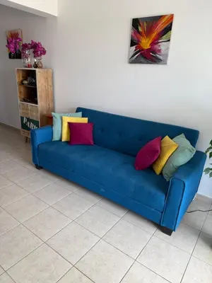 a blue couch with colorful pillows in a living room at Green valley Tersefanou in Tersephanou