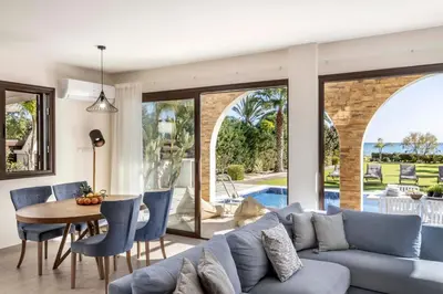 a living room with a blue couch and a table and chairs at Ayia Napa Seafront Ionion Villa H5 in Ayia Napa