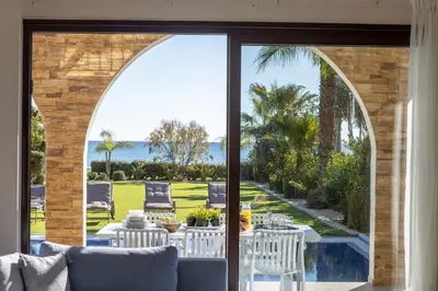 an arched glass door leading to a patio with a table and chairs at Ayia Napa Seafront Ionion Villa H5 in Ayia Napa