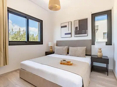a white bedroom with a bed and two windows at Sanders Eduardovich Limassol in Limassol