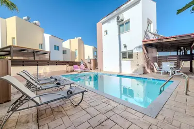 a swimming pool with chairs next to a building at Villa Maria in Protaras