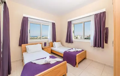 a room with two beds and two windows at Villa Maria in Protaras