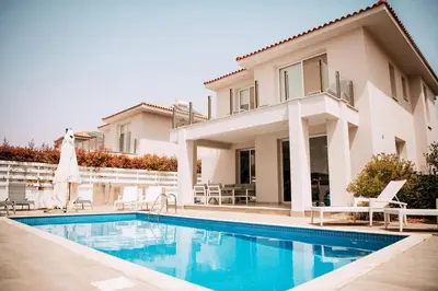 a villa with a swimming pool in front of a house at Jupiter Villa in Voroklini