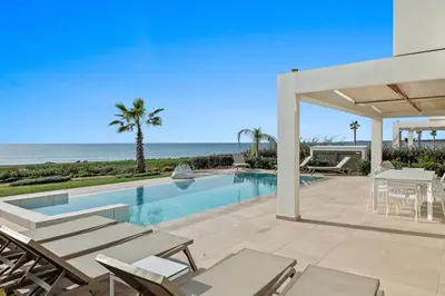 a swimming pool with chairs and the ocean at Serenity Waves Villa 2 in Larnaka