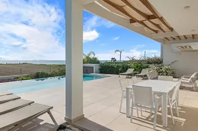 a patio with a table and chairs next to a swimming pool at Serenity Waves Villa 8 in Sophtadhes