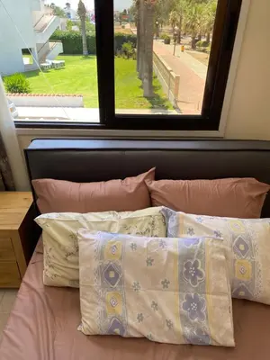 a bed with pillows in front of a window at A sea breeze house in Voroklini