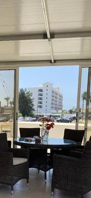 a dining room with a table and chairs and a large window at A sea breeze house in Voroklini