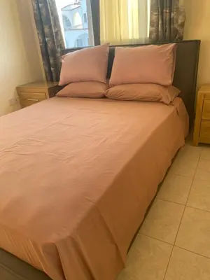 a large bed with pink sheets and pillows at A sea breeze house in Larnaka
