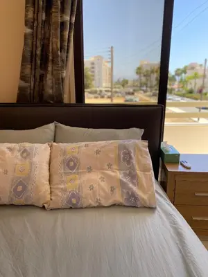 a bed with two pillows and a large window at A sea breeze house in Larnaka