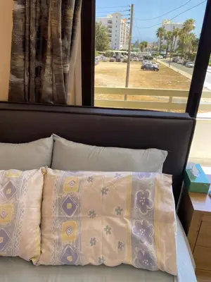 a bed with a pillow in front of a window at A sea breeze house in Larnaka